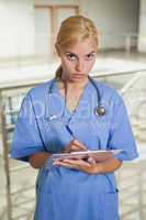 Serious nurse writing on a clipboard