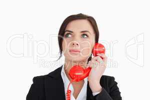 Woman in suit using a red dial telephone