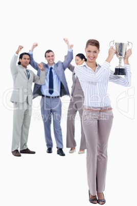 Woman holding a cup with people dressed in suits acclaiming
