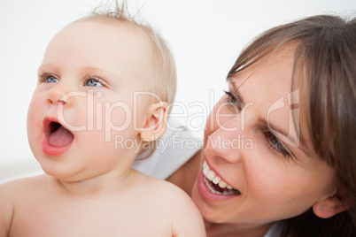Cute baby opening her mouth while being held by her mother