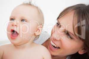 Cute baby opening her mouth while being held by her mother