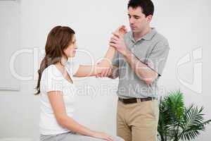 Serious physiotherapist looking at the arm of a woman