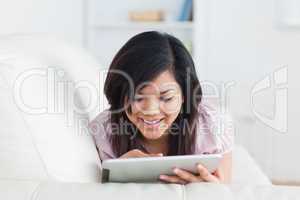 Woman resting on a sofa while touching a tablet