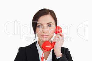 Attractive woman in suit using a red dial telephone