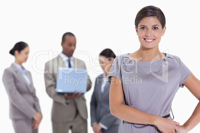 Woman with hands on her hips with business team in the backgroun