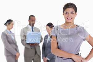 Woman with hands on her hips with business team in the backgroun