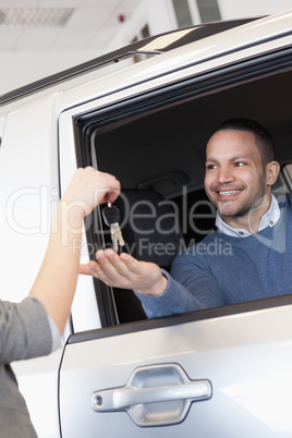 Smiling man in a car receiving a car key