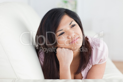 Woman resting on a couch while holding her head with her hand
