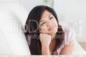 Woman resting on a couch while holding her head with her hand