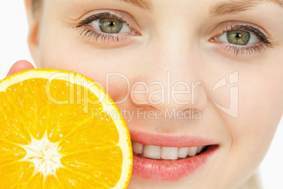 Close up of a woman placing an orange near her lips