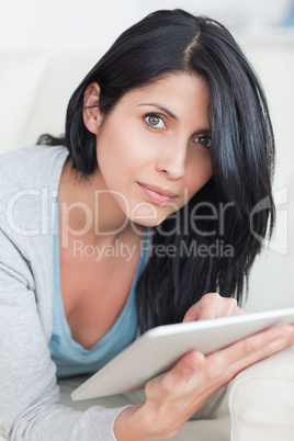Close up of a woman laying on a couch while typing on a tablet