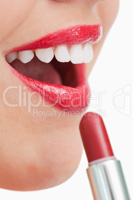 Woman opening her mouth while applying lipstick on her lips