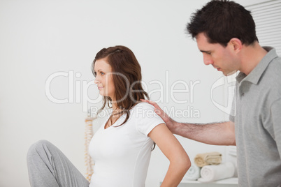 Woman sitting while a man is touching her back