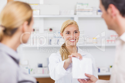 Smiling pharmacist giving a drug bag