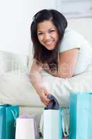 Woman on a couch holding clothes up from a shopping bag