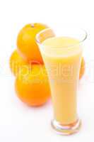 Oranges behind a glass of orange juice