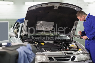 Mechanic holding a clipboard while looking at the engine