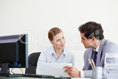 Colleagues talking while holding a sheet