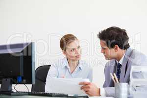 Colleagues talking while holding a sheet