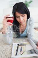 Woman holding a glass of red wine while laying on the floor