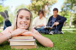 Portrait of a girl lying head on her books in a park