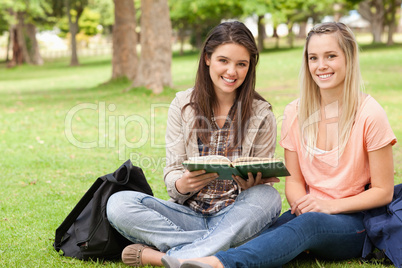 Female teenagers sitting with a textbook