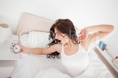 Tired woman holding her alarm clock
