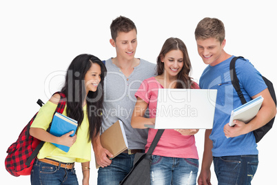 A group looking into a laptop and smiling