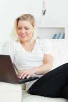 Casual woman sitting on a sofa using a laptop