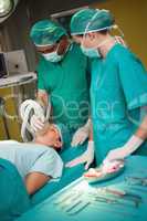 Surgeon working on a patient with a trolley with tools beside th