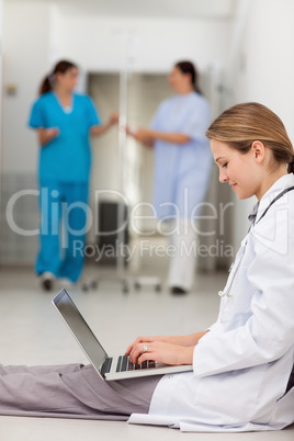 Doctor sitting on the floor while typing on a laptop