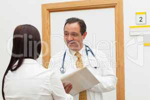 Smiling doctor holding a file while talking to a woman