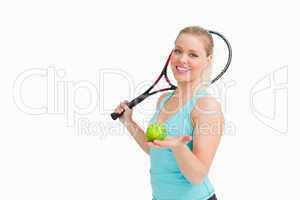 Woman smiling while showing a yellow tennis ball