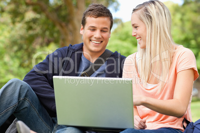 Laughing young people sitting while using a laptop