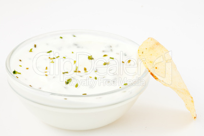 Bowl of white dip with herbs and a chips