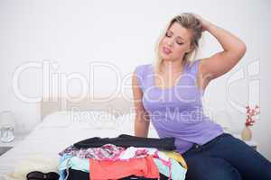 Blonde rubbing her head while looking at her full suitcase