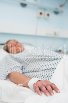 Focus on the hand of a patient lying on a medical bed