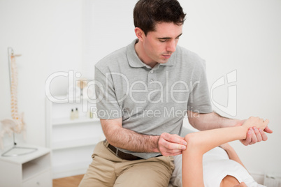 Serious brunette physiotherapist holding the arm of a woman