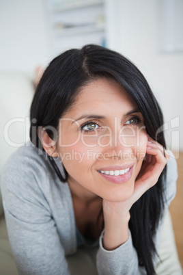 Woman smiling as she holds her head with her palm