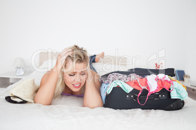 Annoyed woman looking at her full suitcase