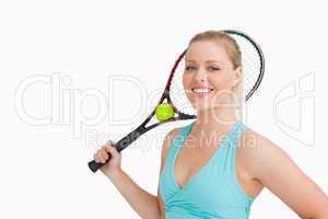 Smiling woman holding a tennis raquet and ball
