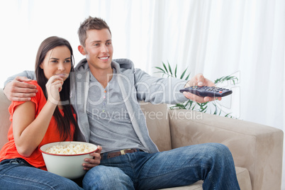 Side view shot of a couple smiling as they change the tv channel