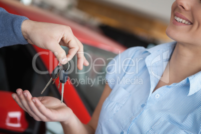 Smiling woman receiving keys from somebody