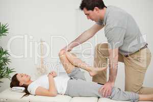 Serious doctor stretching the leg of a woman