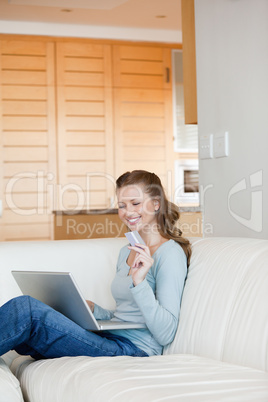 Woman using a laptop while holding a card