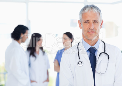 Mature and calm doctor standing upright in front of his medical
