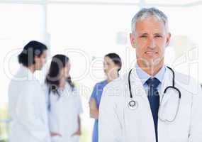Mature and calm doctor standing upright in front of his medical