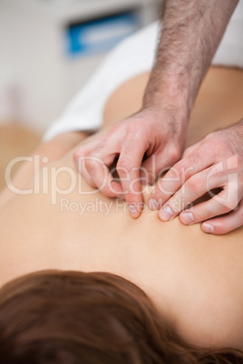 Back of a woman being massaging while fingertips of doctor