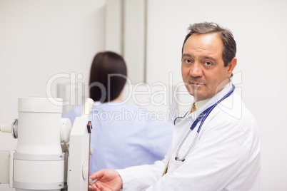 Doctor checking a machine while a patient is having a mammograph