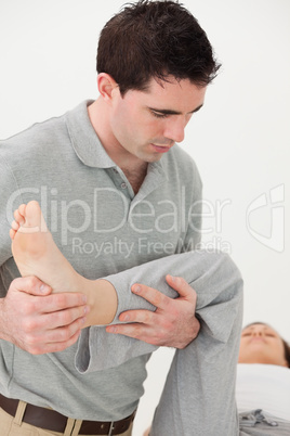 Chiropractor holding the leg of his patient while moving it